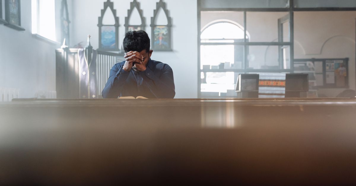 A man in prayer in a sunlit room, reflecting spirituality and peace.